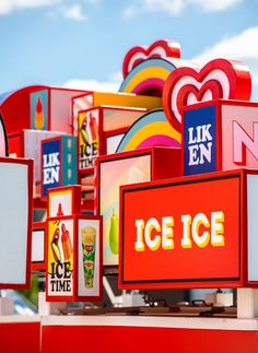 many ice cream signs are stacked on top of each other with the sky in the background