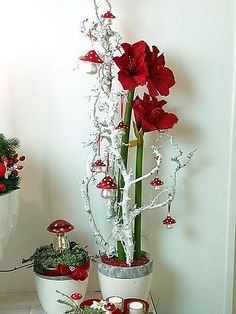 a table topped with vases filled with red flowers and candles covered in tinsel