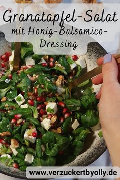 a person is cutting into a salad with greens and pomegranates on it