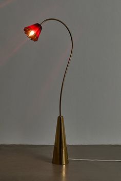 a floor lamp with a red light on it's side and a white wall in the background