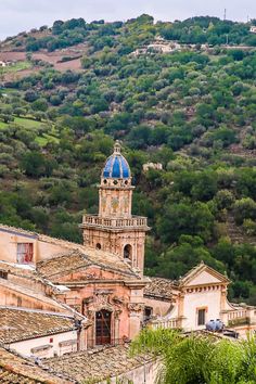 an old building with a blue dome sits on top of a hill in the middle of town