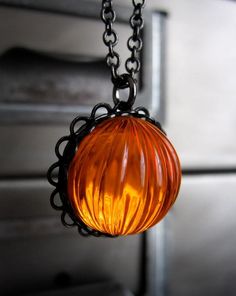 an orange glass ball hanging from a black chain