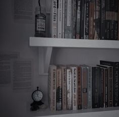 there are many books on the shelves and a clock is next to each other in front of them