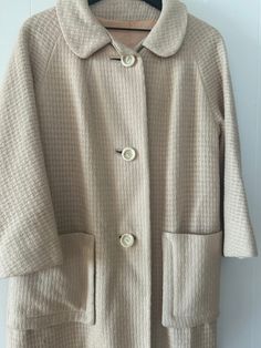 "Women's vintage winter wool coat jacket  Cream with peach lining  From Paul R Nissen  Mr. Nissen started his firm, located at 325 W. Jackson Blvd., in 1941. It specialized in petite sizes, and was the first to market size 1 for women. He was also a pioneer in creating a middle price range of clothing for college-age youth. Among his customers were specialized shops in large department stores as well as apparel stores in college and university towns. Coat is not marked with a size - please see measurements and message me with questions  Shoulder to shoulder 18\" Shoulder to cuff 21\" (this seems to sit right above the wrist which was a popular style in the 50s)  Neck to bottom measures 39\" long" Cream Winter Blazer With Pockets, Winter Cream Blazer With Pockets, Cream Blazer With Pockets For Winter, Vintage Long Pea Coat For Spring, Retro Cream Outerwear For Fall, Spring Vintage Long Pea Coat, Retro Beige Long Coat, Vintage Wool Coat With Pockets, Vintage Cream Outerwear With Button Closure