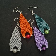 three different colored earrings with beads on them sitting on a black surface next to each other