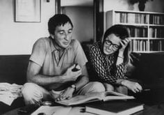 a man and woman sitting on top of a couch next to each other reading books