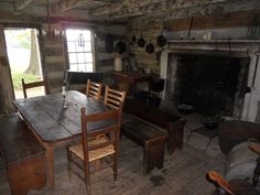 an old log cabin with wooden tables and chairs in front of a fire place on the wall