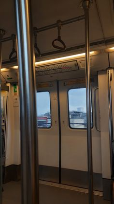 the inside of a subway car with its doors open and windows showing cityscape