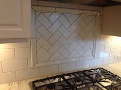 a stove top oven sitting next to a white tiled backsplash in a kitchen