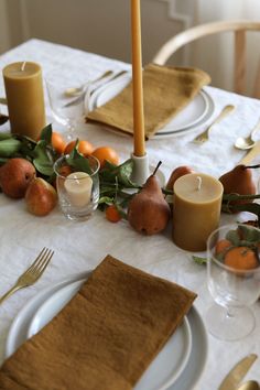 the table is set with candles, fruit and other things to decorate it for dinner