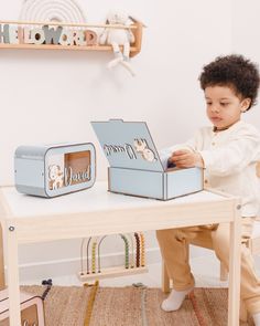 a little boy sitting at a table playing with a box