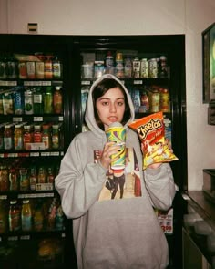 a girl in a hoodie holding a bag of chips