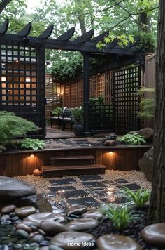 an outdoor garden with rocks and plants in the foreground, lit up by lights