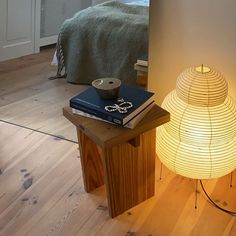 a lamp sitting on top of a wooden table next to a book and a cup