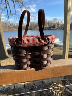 two brown baskets sitting on top of a wooden bench next to a body of water