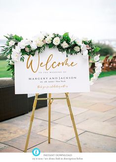 a welcome sign with flowers and greenery is displayed on a wooden easel for an outdoor ceremony