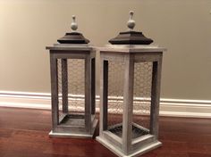 two metal lanterns sitting on top of a hard wood floor