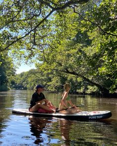 two people are sitting on a paddle board in the water