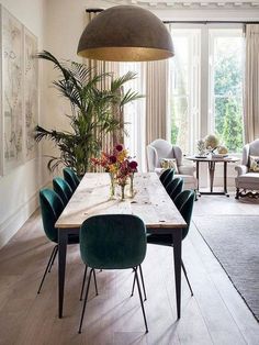 a dining room table with green chairs and a large potted plant in the center