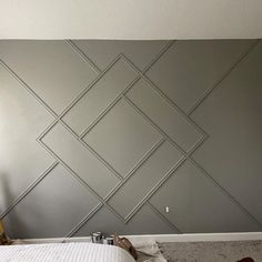 a bed sitting in a bedroom next to a wall with geometric design painted on it