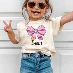 Custom Kids Name Back To School Shirt Shirt, Toddler First Day of School Tee Kindergarten Shirt With Name, Pink Bow Coquette First Day School Outfit Baby Bodysuit With Name 🌸 Soft & Lightweight Material - Graphic tees for women are made from a soft, lightweight, and stretchy fabric that provides a familiar and comfortable feel. You'll love wearing it all day long. 🌸 GREAT GIFT:  Good choice as a gift for your mom, sister, your wife or anyone you want to send a gift.  🌸 Wash: Recommended machi First Day School, Bow Coquette, Kindergarten Shirts, School Tees, Custom Kids, Gifts For Your Mom, Tees For Women, School Shirts, School Outfit