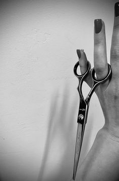 a pair of scissors held in the air by someone's hand with their fingers