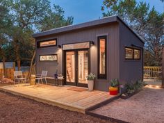 a small house with a deck in the middle of it's backyard area at night