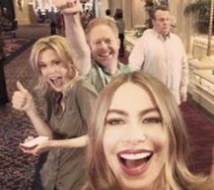 two women and one man are standing in a mall with their arms up, smiling at the camera