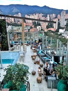 people are sitting at tables on the roof of a high rise building with an outdoor swimming pool