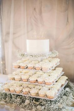 a three tiered cake with cupcakes on top