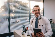 a man in a doctor's coat is holding a tablet