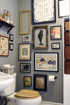 a white toilet sitting in a bathroom next to a wall filled with pictures and frames