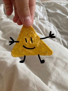 a hand holding a piece of cheese with a smiley face drawn on it's side