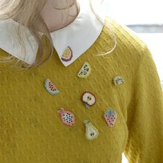 a close up of a person wearing a yellow sweater with buttons on the collar and sleeves