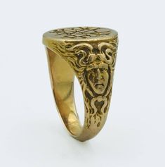 This Art Nouveau era yellow gold ring, dated inside 1900, is a fine example of the period's aesthetic, which often included fluid, organic forms and mythological motifs. The band features a figural depiction of Medusa, a nod to the era's fascination with Greco-Roman themes and figures, finely crafted from 15 karat yellow gold ring size 5 3/4, weighs 9.6 grams. The face of the ring presents a monogram or inscription, typical of personalization in jewelry of this time. Art Nouveau jewelry often reflected a departure from the rigid forms of the Victorian era, embracing instead the flowing lines and natural forms that have come to define the movement. All of our pieces are in as found condition, we just lightly clean them never polish, polish only upon request which nullifies the return option Symbolic Brass Rings For Formal Occasions, Gold Art Nouveau Jewelry With Intaglio, Victorian Yellow Gold Engraved Ring With Intaglio, Victorian Engraved Yellow Gold Ring With Intaglio, Antique Gold Signet Ring Collectible, Antique Yellow Gold Round Signet Ring, Art Nouveau Yellow Gold Ring, Symbolic Yellow Gold Brass Signet Ring, Vintage Engraved Ring With Historical Design