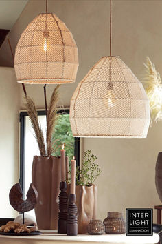 three lamps hanging from the ceiling above a table with vases and candles on it