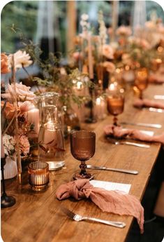 a long wooden table with candles and napkins on it, along with other place settings