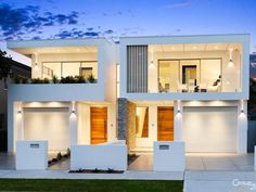 a modern house with two garages and lights on the front door, in an urban setting