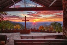 the sun is setting at the top of a hill with benches in front of it