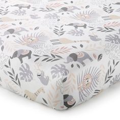 an image of a baby crib sheet with elephants and leaves on the coverlet