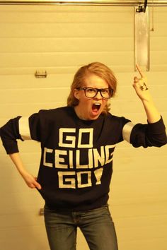 a woman with glasses and a black shirt is holding up her hands in the air