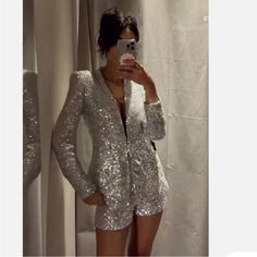 a woman taking a selfie in front of a mirror wearing silver sequins