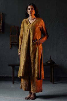 Antique gold flared kurta in a handloom tissue base with embroidery on the sleeve hems. Comes with farshi pants.
Component: 2
Pattern: Embroidery
Neckline: V neck
Sleeve Type: Full
Fabric: Handloom Tissue; Lining: Shantoon
Color: Gold
Other Details: 
Pockets on the sides
Side slits
Note: Dupatta worn by the model is not for sale
Occasion: Puja - Aza Fashions V Neck Pattern, Embroidery Neckline, Gold Suit, Black Lehenga, Modern Suits, Traditional Suit, Kurta Patterns, Pakistani Wedding Outfits, A Line Kurta