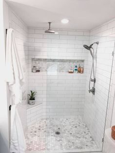 a white tiled bathroom with shower and toilet