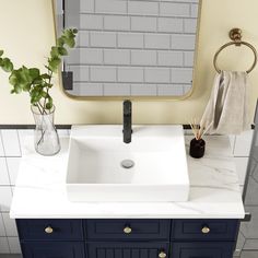 a white sink sitting under a bathroom mirror next to a vase with flowers in it