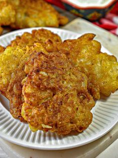 some fried food on a white plate with ranch dressing in the background and a red and white checkered table cloth