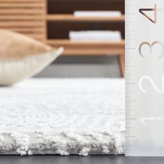 a white rug with a ruler on it next to pillows and a wooden table in the background