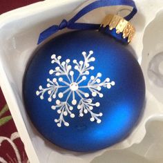 a blue ornament with white snowflakes on it sitting in a box