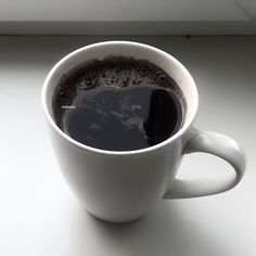 a white cup filled with liquid on top of a table