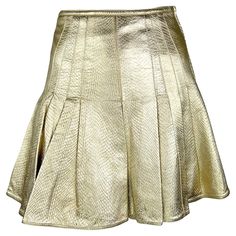 This metallic gold leather flare skirt, designed by Gianni Versace for his Fall/Winter 1994 collection, is a striking example of his bold, glamorous aesthetic. The lavender version of this reptile-embossed skirt was modeled by Kate Moss as part of runway look 59 and also featured in the season's ad campaign with Christy Turlington, photographed by Richard Avedon. Crafted from embossed leather, this high-waisted skirt boasts a pleated flare hem that adds movement and drama. Recently worn by Margo Film Barbie, Leather Flare Skirt, Glamorous Aesthetic, Versace Skirt, Pleated Flare Skirt, Cutout Skirt, Versace Runway, Robes Vintage, Versace Brand